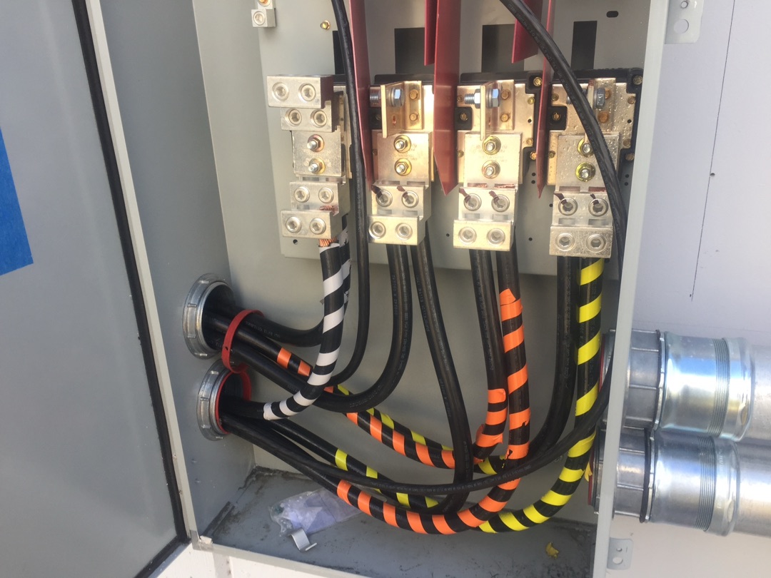 Color-coded phase wiring with striped tape identification connected to copper bus bar lugs in a commercial disconnect by Burlingame Brothers Electric