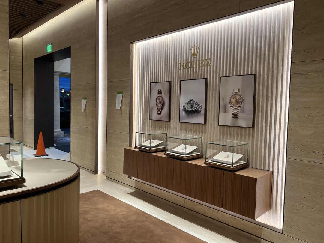 Rolex wall gallery with backlit fluted panel, framed watch photography, and illuminated glass display cases — electrical installation by Burlingame Brothers Electric